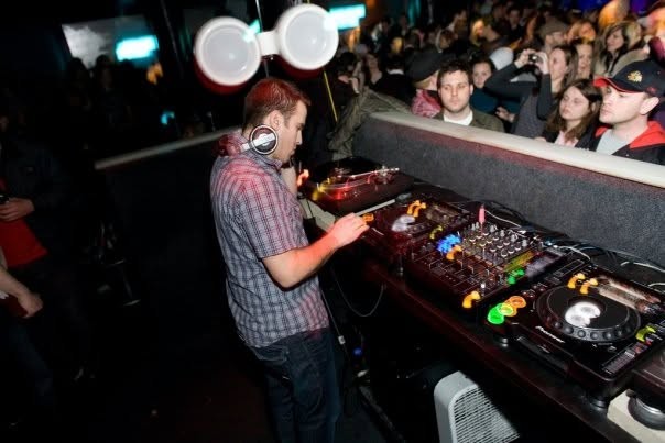 Brian Ffar in the DJ booth with the crowd behind him